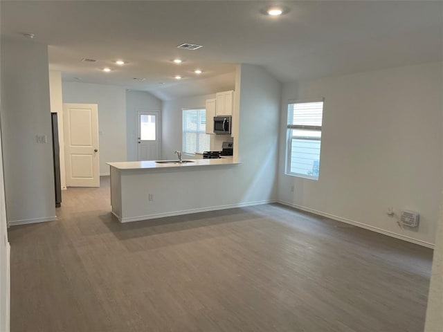 kitchen featuring lofted ceiling, kitchen peninsula, stainless steel appliances, light hardwood / wood-style floors, and white cabinets