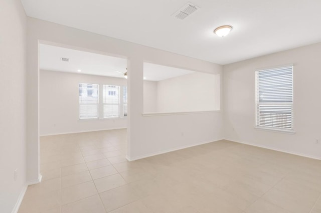 unfurnished room featuring light tile patterned flooring, visible vents, ceiling fan, and baseboards