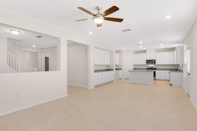 kitchen with visible vents, a kitchen island, baseboards, appliances with stainless steel finishes, and white cabinets