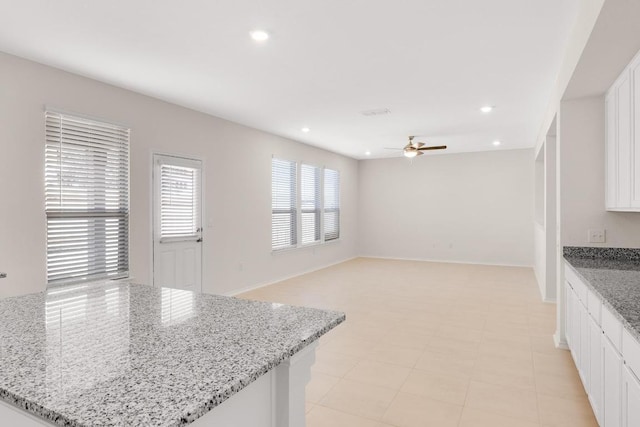 kitchen featuring white cabinetry, recessed lighting, baseboards, ceiling fan, and light stone countertops