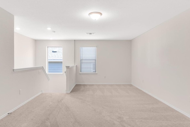 unfurnished room with light colored carpet and baseboards