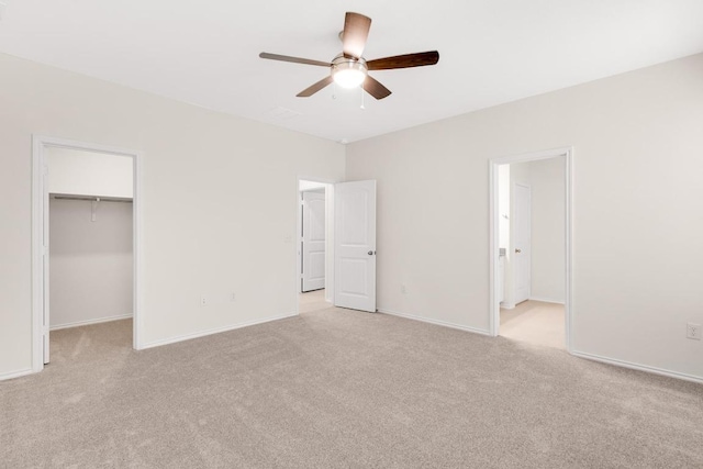 unfurnished bedroom with a spacious closet, baseboards, and light carpet