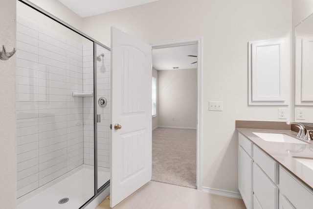 bathroom with tile patterned flooring, tiled shower, vanity, and baseboards