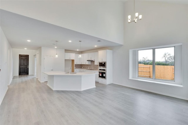 kitchen with light countertops, appliances with stainless steel finishes, light wood-style floors, a sink, and under cabinet range hood