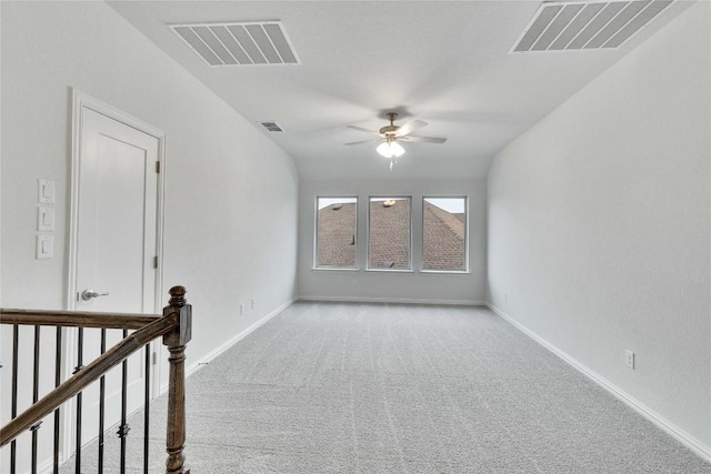 spare room with a ceiling fan, visible vents, and light carpet