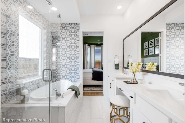 bathroom with tiled bath, plenty of natural light, and vanity