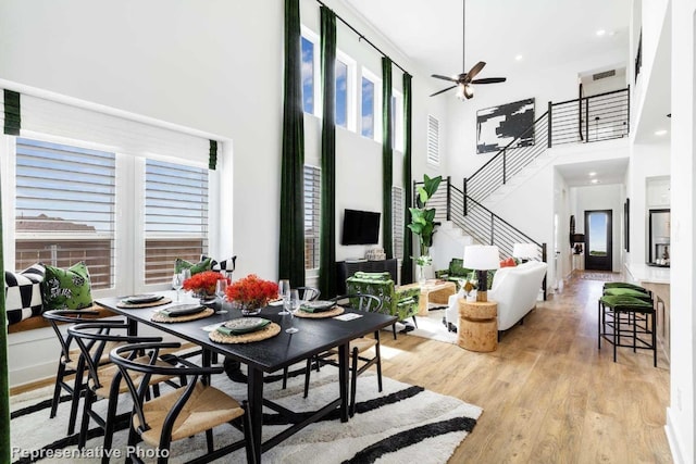 dining space with a towering ceiling, light hardwood / wood-style floors, and ceiling fan