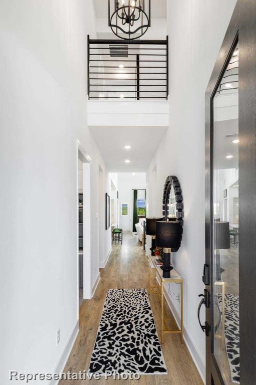 entryway with a notable chandelier, wood-type flooring, and a towering ceiling