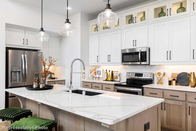 kitchen featuring white cabinetry, a large island, stainless steel appliances, tasteful backsplash, and light stone counters