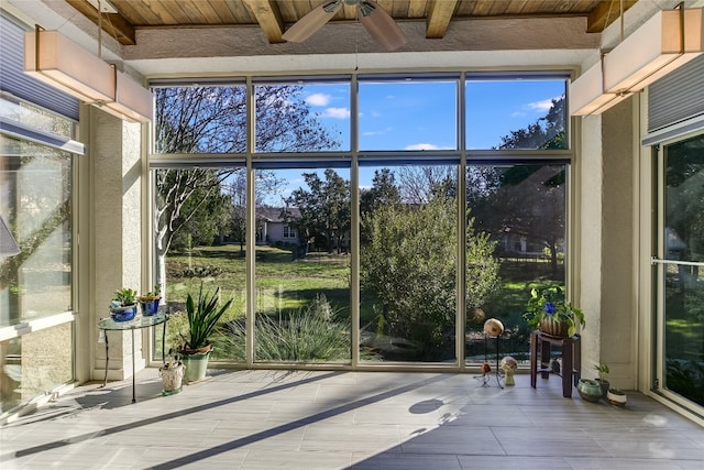 sunroom with beamed ceiling, ceiling fan, and wooden ceiling