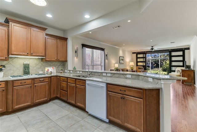 kitchen with kitchen peninsula, white appliances, light stone counters, and ceiling fan