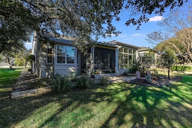 rear view of property with a lawn and a sunroom