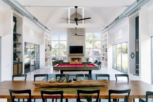 dining room featuring plenty of natural light, a fireplace, pool table, and a high ceiling