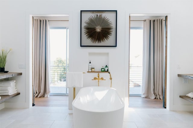 bathroom with a tub to relax in and tile patterned floors