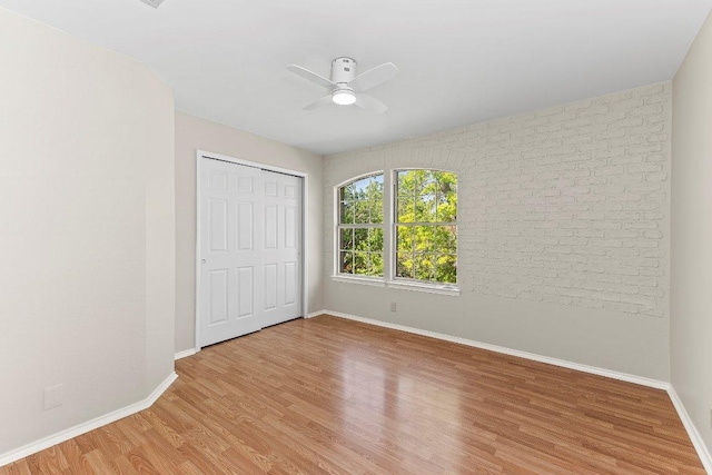 1807 Iris Ln, Cedar Park, TX 78613 - unfurnished bedroom with wood finished floors, baseboards, a closet, brick wall, and a ceiling fan