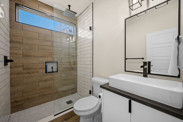 bathroom with tiled shower, vanity, and toilet