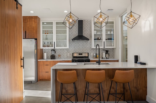409 W Odell St Unit 2, Austin, TX 78752 - kitchen with stainless steel appliances, wall chimney range hood, brown cabinetry, a sink, and decorative backsplash