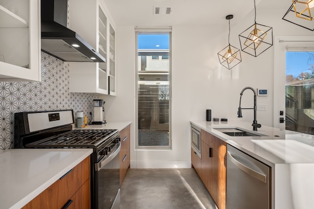 kitchen featuring white cabinets, wall chimney range hood, sink, and appliances with stainless steel finishes