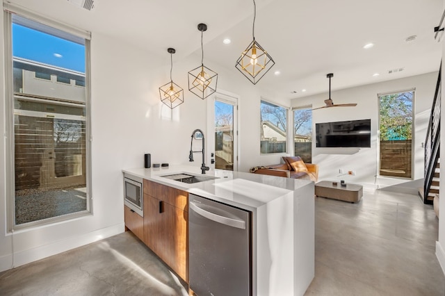 kitchen with kitchen peninsula, appliances with stainless steel finishes, decorative light fixtures, and sink