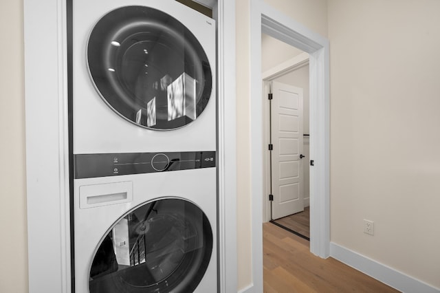 washroom with light hardwood / wood-style flooring and stacked washer and clothes dryer