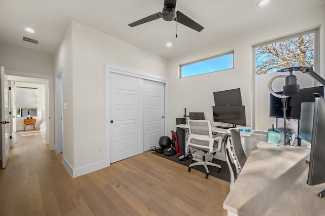 office with light wood-type flooring and ceiling fan