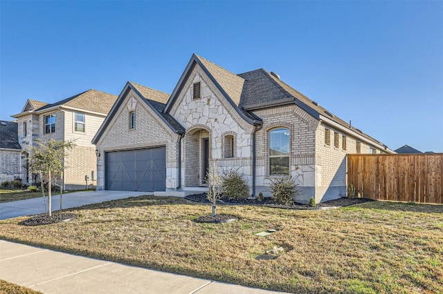 view of front facade featuring a garage, driveway, brick siding, fence, and a front yard