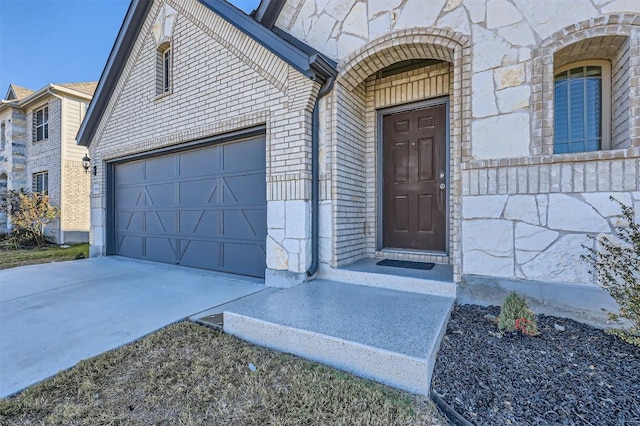 doorway to property featuring concrete driveway, stone siding, brick siding, and an attached garage