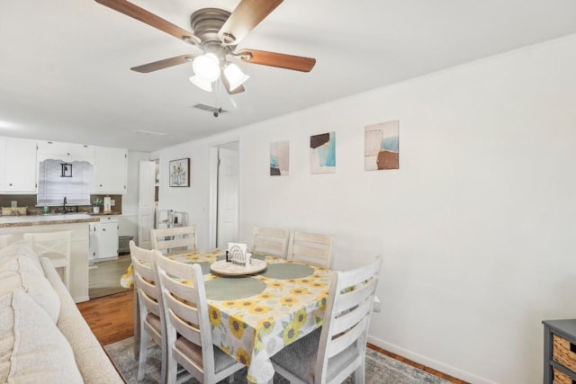 dining room featuring ceiling fan, sink, and light hardwood / wood-style floors