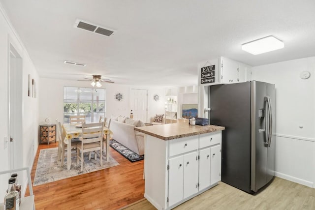 kitchen with visible vents, a peninsula, white cabinets, stainless steel fridge with ice dispenser, and light wood finished floors