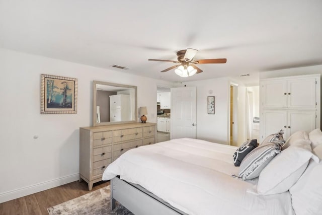 bedroom with ceiling fan, wood finished floors, visible vents, and baseboards