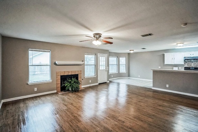 unfurnished living room with hardwood / wood-style flooring, ceiling fan, a fireplace, and a textured ceiling