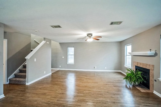 unfurnished living room featuring ceiling fan, dark hardwood / wood-style flooring, and a tiled fireplace