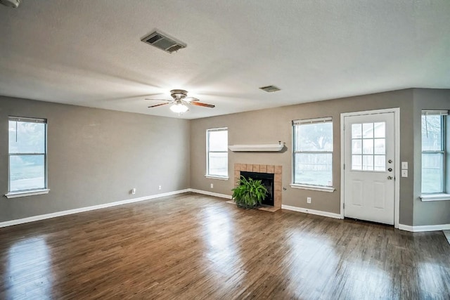 unfurnished living room featuring a textured ceiling, ceiling fan, a fireplace, and dark hardwood / wood-style floors