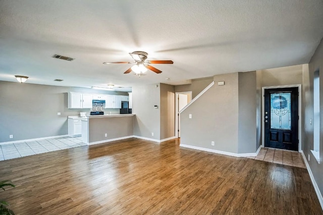 unfurnished living room with ceiling fan, light hardwood / wood-style floors, and a textured ceiling