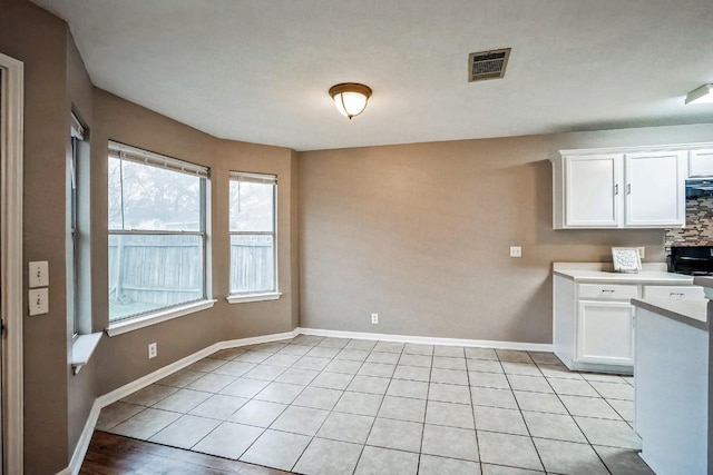 kitchen with light tile patterned flooring, white cabinetry, and tasteful backsplash