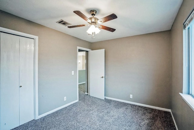 unfurnished bedroom featuring carpet flooring, ceiling fan, multiple windows, and a closet