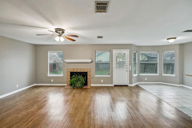 unfurnished living room featuring a fireplace, a textured ceiling, tile patterned floors, and ceiling fan