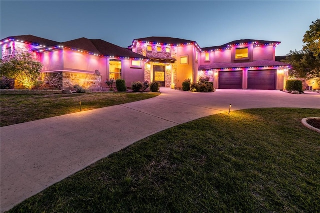 mediterranean / spanish-style home with stucco siding, stone siding, concrete driveway, and a front lawn