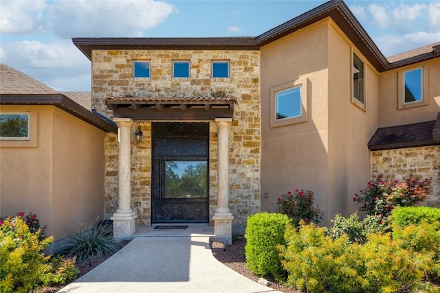 view of exterior entry with stone siding and stucco siding