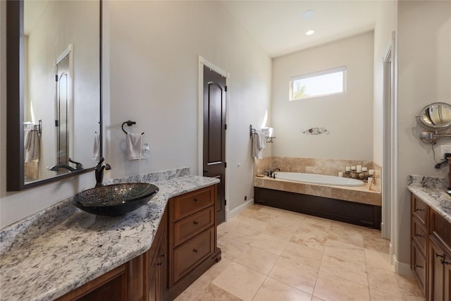 bathroom with baseboards, two vanities, a sink, tile patterned flooring, and a garden tub