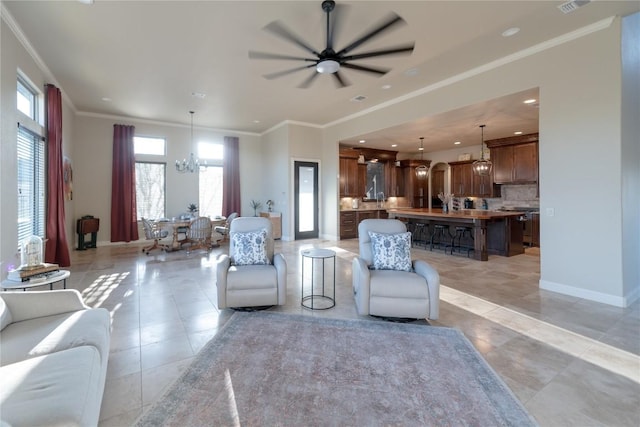 living room with light tile patterned floors, baseboards, ceiling fan with notable chandelier, crown molding, and recessed lighting