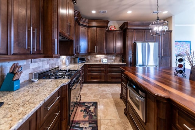 kitchen with tasteful backsplash, decorative light fixtures, stainless steel appliances, dark brown cabinets, and wooden counters