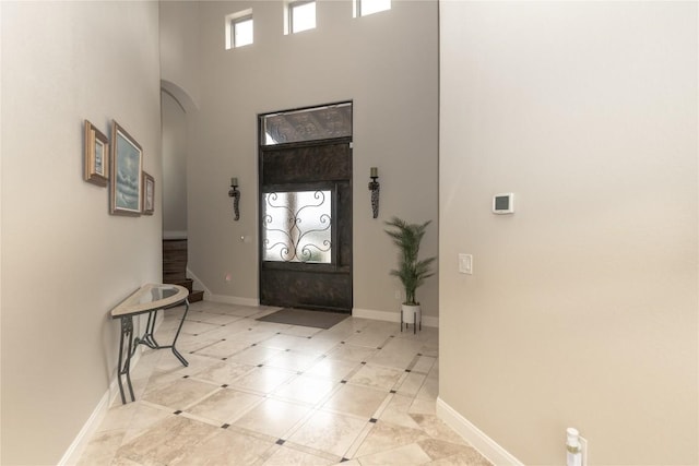 entrance foyer with stairway, a high ceiling, baseboards, and arched walkways