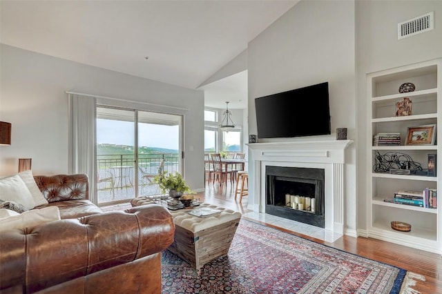 living room featuring wood-type flooring, built in features, and high vaulted ceiling