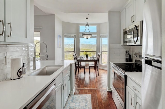 kitchen featuring sink, stainless steel appliances, decorative light fixtures, decorative backsplash, and white cabinets