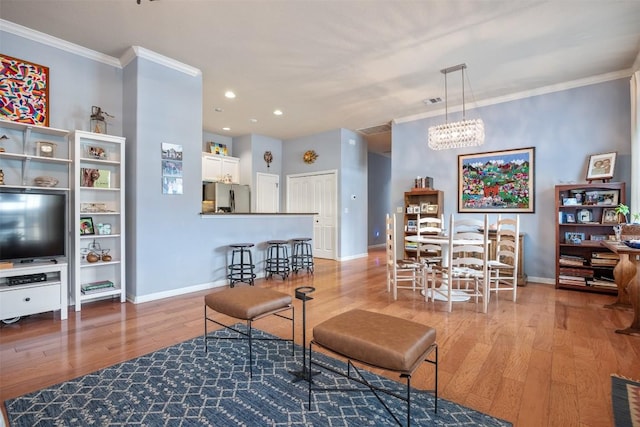 living room with light wood-type flooring, ornamental molding, and a chandelier