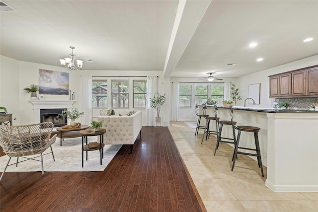 living room featuring ceiling fan with notable chandelier, a healthy amount of sunlight, light tile patterned flooring, and sink