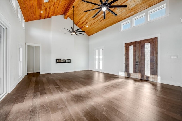 unfurnished living room with wood ceiling, beamed ceiling, a towering ceiling, and dark wood-type flooring