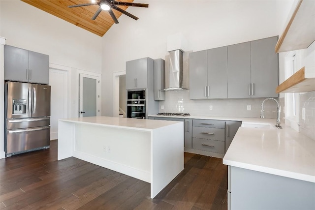 kitchen with stainless steel appliances, sink, wall chimney range hood, wooden ceiling, and a kitchen island