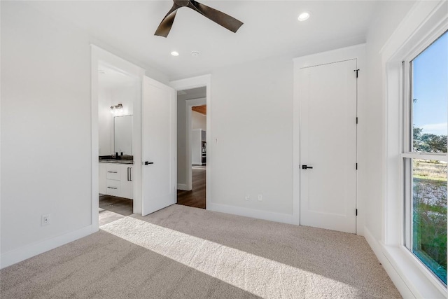 unfurnished bedroom featuring ceiling fan, light colored carpet, and connected bathroom